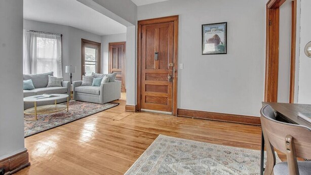 A spacious living room with hardwood flooring, a large wooden door, and a framed picture on the wall. - Ideal & Exquisite Elmwood Village Victorian (Buffalo)