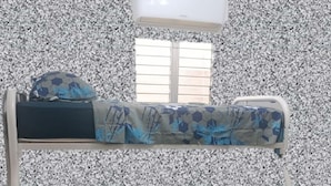 Una cama litera con ropa de cama estampada, una ventana con persianas y un equipo de aire acondicionado arriba.