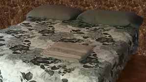 Una cama con colcha estampada de flores y dos almohadas.