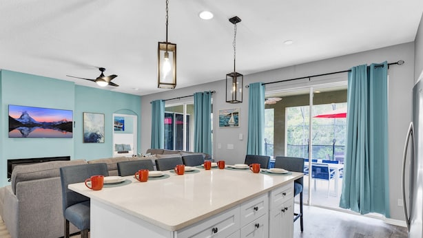 A modern kitchen with a central island, dining area, and a view to an outdoor patio.