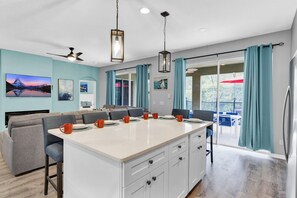 A modern kitchen with a central island, dining area, and a view to an outdoor patio.