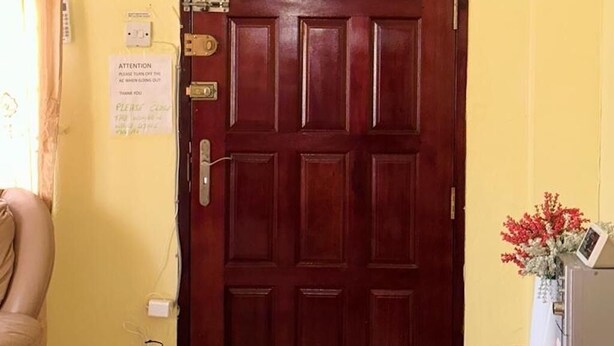 Una porta de fusta amb una maneta de bronze, un cartell que demana apagar l'aire condicionat i una unitat de aire condicionat penjada a sobre.