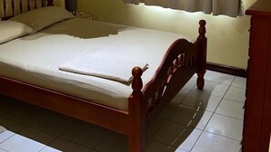 Un dormitori amb un llit, una mosquiteria penjant, una finestra amb cortines i un aparell d'aire condicionat.