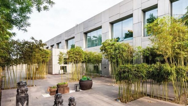 A modern building with a courtyard featuring tall bamboo plants and decorative stone lions. - Hongkou Silver Hotel (Tianjin)