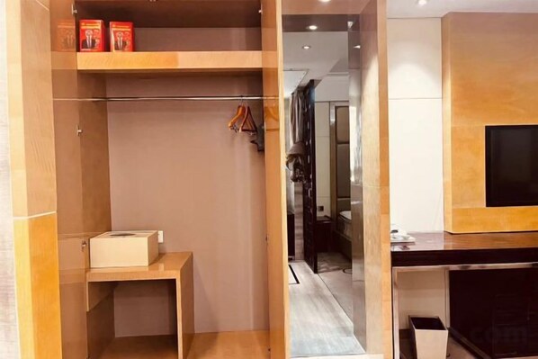 A hotel room with a wooden wardrobe, a small table, and a television mounted on the wall.