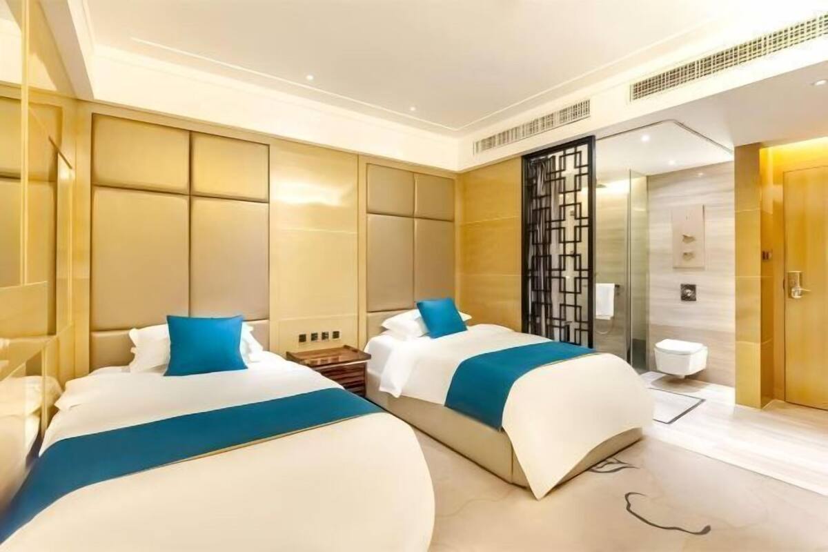 A hotel room with two beds, a shower area, and a bathroom.