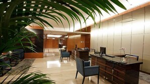 A modern lobby with a reception desk, seating area, and large potted plants. - Hongkou Silver Hotel (Tianjin)