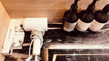 A bathroom with a marble countertop, a white power strip, and four bottles of shampoo.