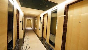 A hotel hallway with doors on both sides, a patterned carpet, and a ceiling with a textured design.