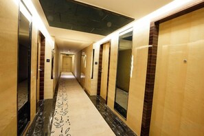 A hotel hallway with doors on both sides, a patterned carpet, and a ceiling with a textured design. - Hongkou Silver Hotel (Tianjin)