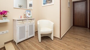 A hallway with a white chair, a white cabinet with a mirror, and a wooden door. - Amore&Psiche - De Vivo Realty Sorrento (Sorrento)