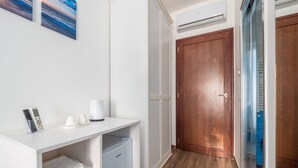 A hallway with a white console table, a coffee machine, and a mini-fridge. There is a wooden door and a glass door leading to another room. - Amore&Psiche - De Vivo Realty Sorrento (Sorrento)