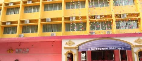 A multi-story hotel with a yellow facade, a red lower section, and a blue entrance with a sign.