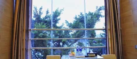 A hotel room with a large window, a small table, two chairs, and a bed.
