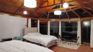 Una camera da letto con due letti, un soffitto in legno e vista sulla città di notte.