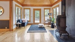 Una habitación amplia con vigas de madera, ventanas grandes, una chimenea y un rincón de estar acogedor.