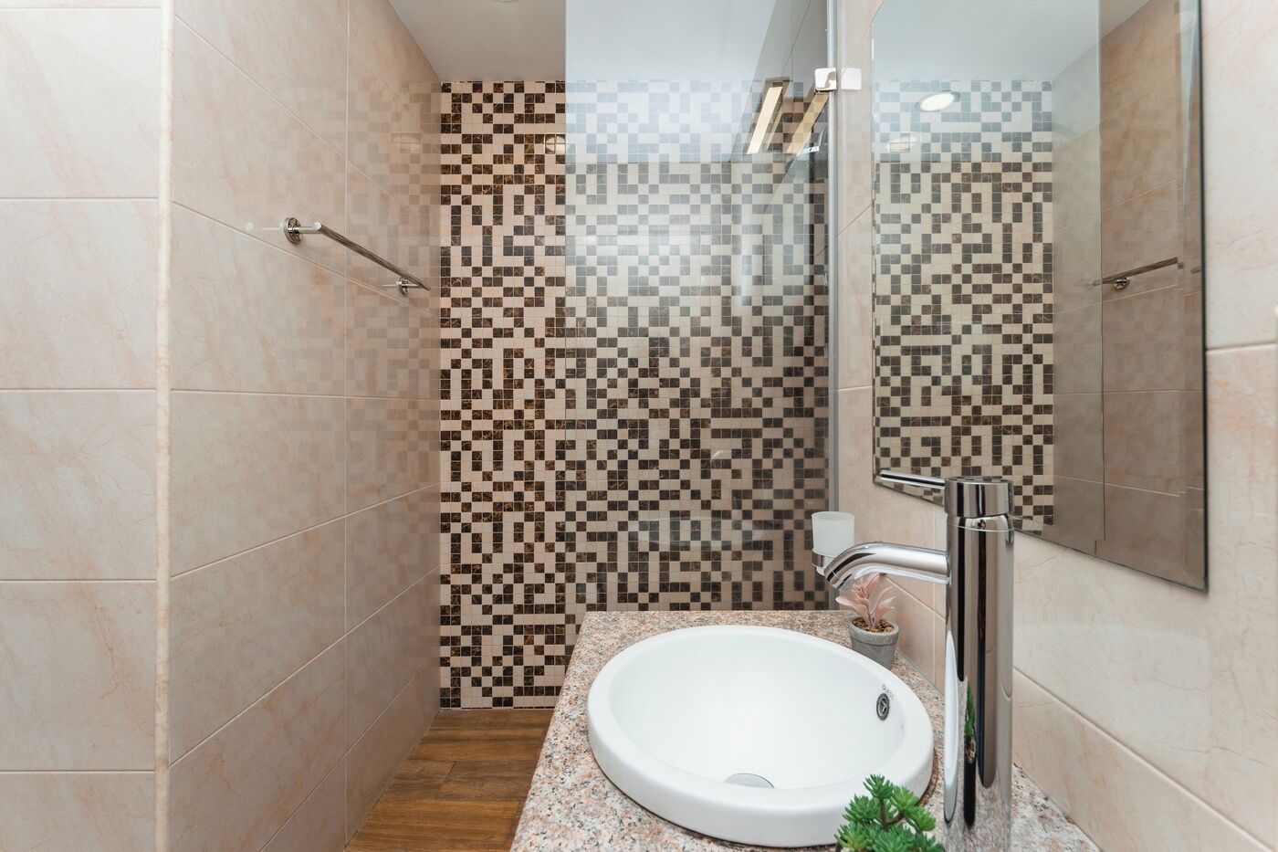 A bathroom with a tiled shower, a sink with a faucet, and a mirror.