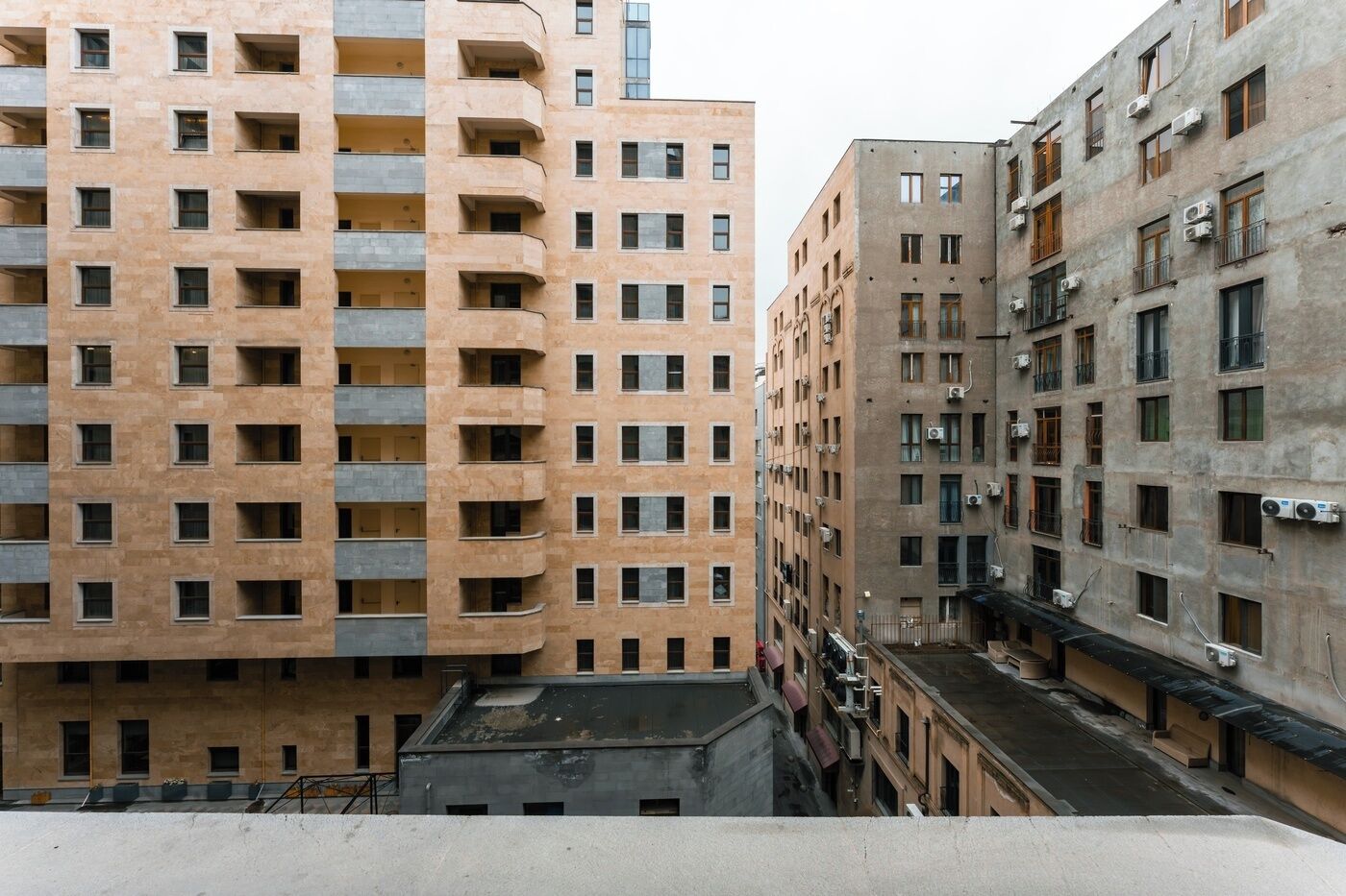 A multi-story building with balconies, a flat roof, and air conditioning units.