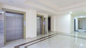 A clean, modern lobby with three elevators and a tiled floor.