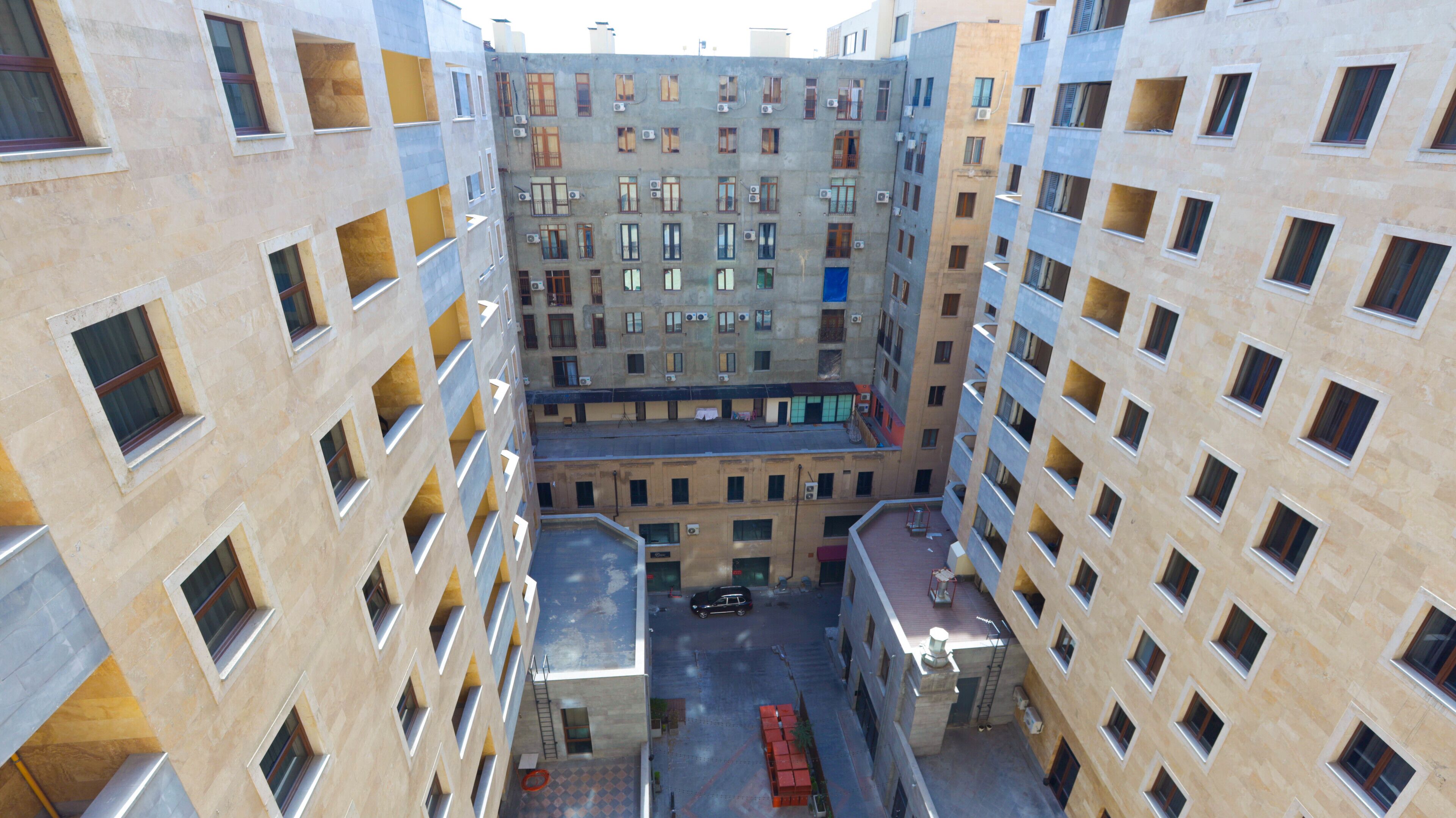 Un immeuble résidentiel à plusieurs étages doté d’une cour intérieure, de balcons et d’un espace de stationnement.