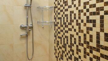 A shower with a handheld showerhead, a wall-mounted faucet, and a handheld showerhead.