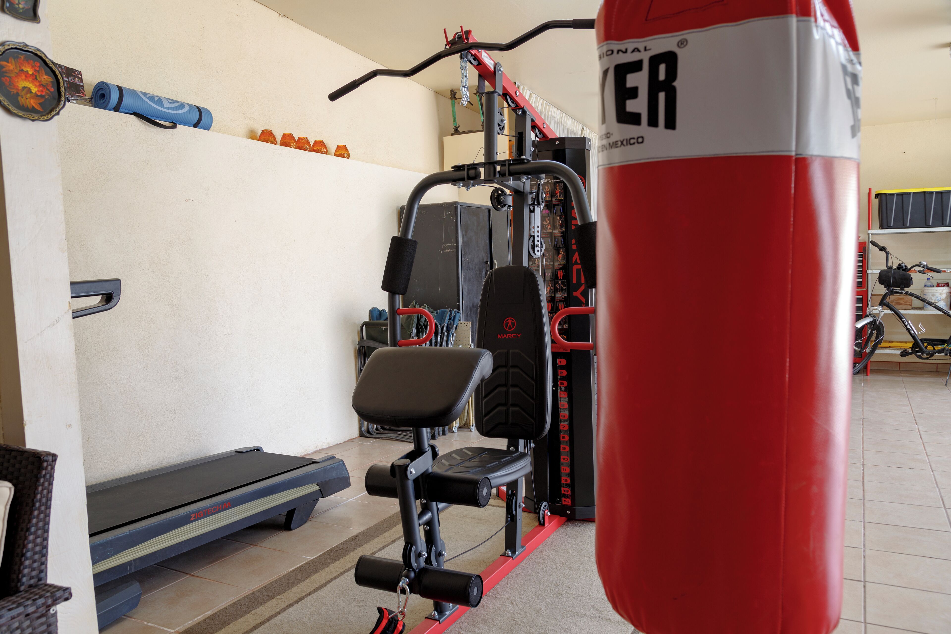 A gym with exercise equipment, a punching bag, and a treadmill.