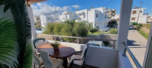 A balcony with a table and chairs, overlooking a residential area with modern buildings and a parked car. - Gennadi Retreat - House 2 (Rhodes)