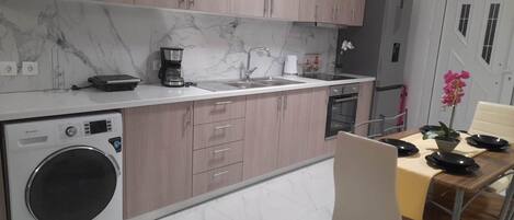 Una cocina moderna con lavadora integrada, cafetera y lavamanos.