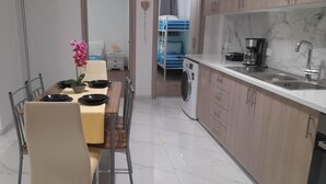 A compact kitchen with a dining area, a washing machine, and a heart-shaped decoration on the wall. - Gennadi Retreat - House 2 (Rhodes)