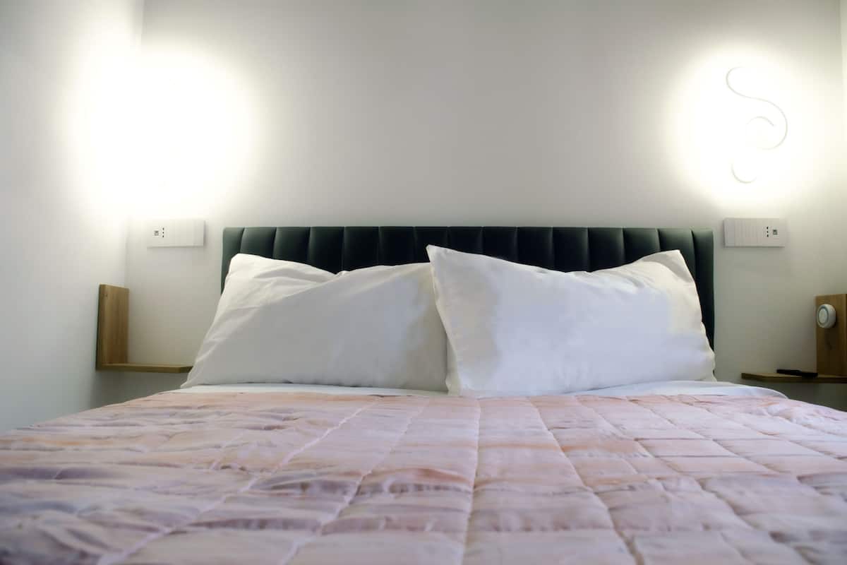 A neatly made bed with a quilted cover, two white pillows, and a dark headboard.
