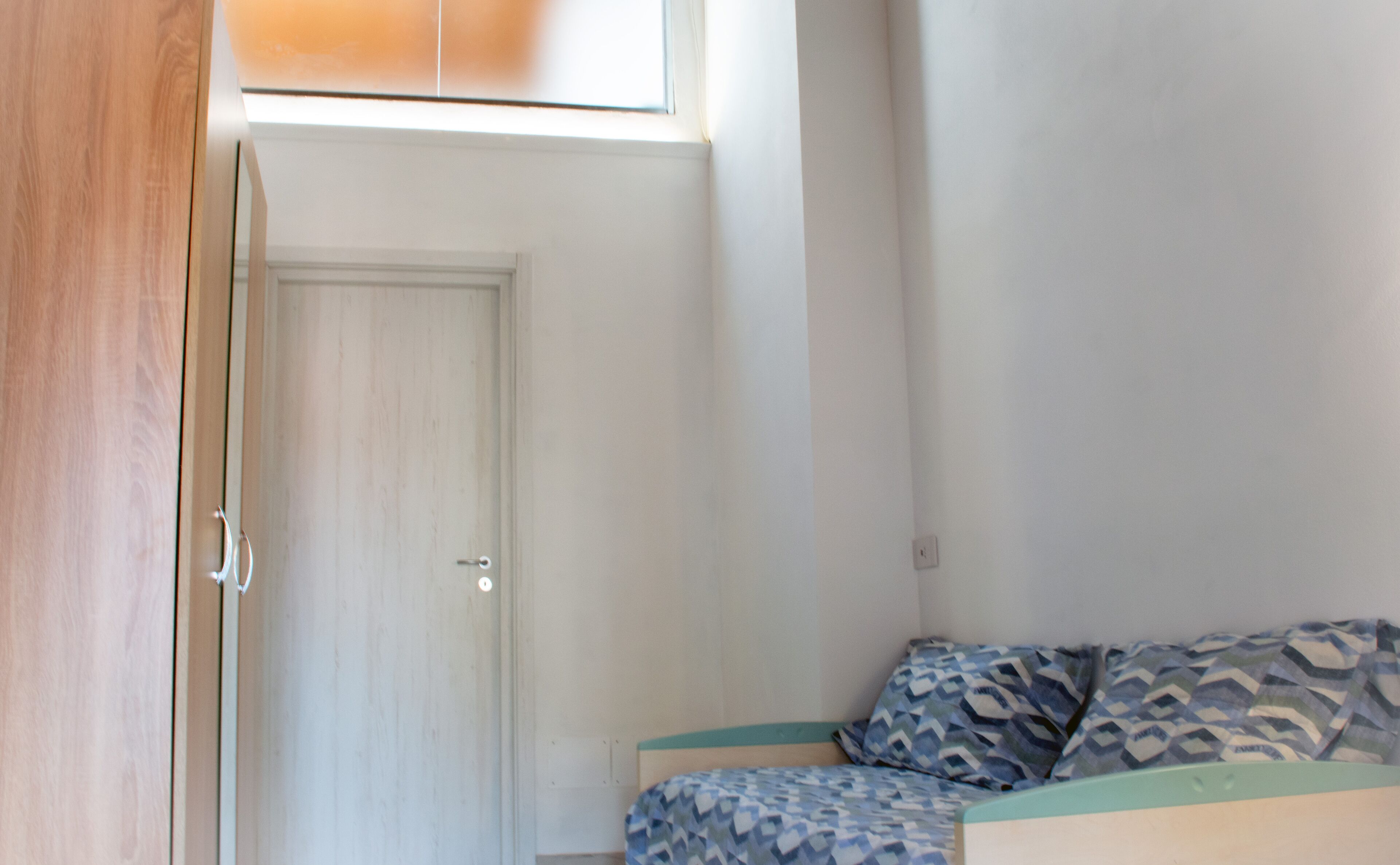 Une chambre à coucher avec un lit, une porte et une fenêtre.