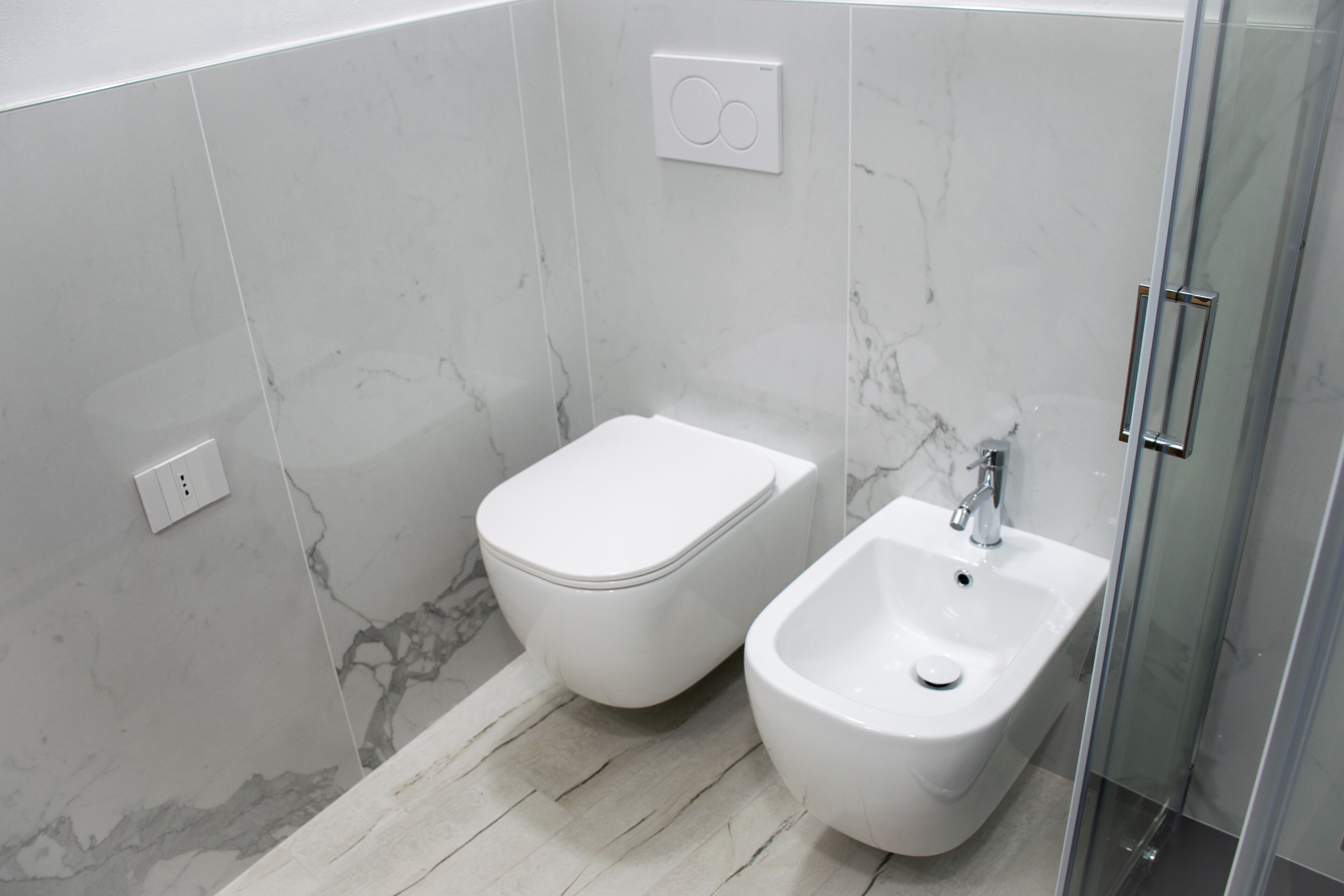 Un baño moderno con inodoro, bidé y cabina de ducha de vidrio.