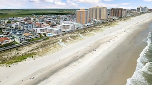 Un paisaje urbano costero con una playa amplia y arenosa, edificios altos y un cielo despejado.