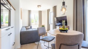 A modern dining area with a round table, chairs, and a fruit bowl. - Villa Dornkamp - Apartment 1 - Vacation in style. Close to the beach. Modern. Central. (Timmendorfer Strand)