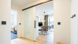 A modern interior with a glass door leading to a dining area and a kitchen. - Villa Dornkamp - Apartment 1 - Vacation in style. Close to the beach. Modern. Central. (Timmendorfer Strand)