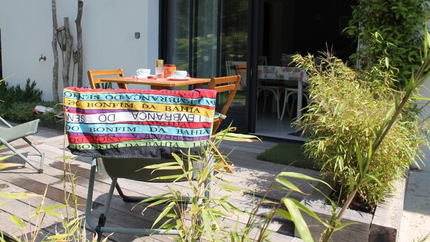 An outdoor seating area with a table and chairs, a potted plant, and a wooden deck. - CLASS 3* STUDIO 1 MINUTE FROM THE BEACH (Andernos-les-Bains)