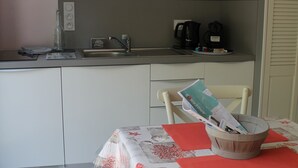 A compact kitchen with a microwave, coffee maker, and kettle. There is a dining table with chairs and a basket. - CLASS 3* STUDIO 1 MINUTE FROM THE BEACH (Andernos-les-Bains)