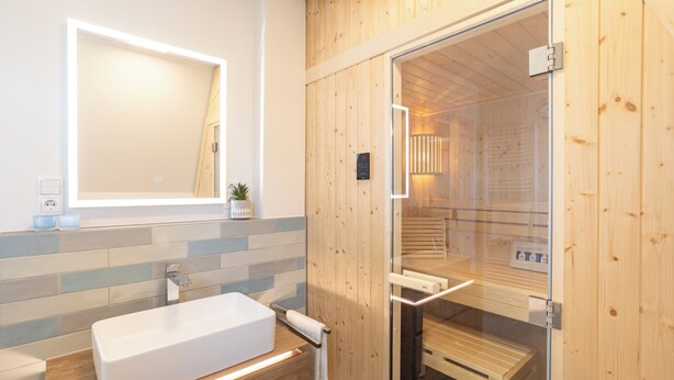 A modern bathroom with a wooden interior, a glass shower enclosure, and a white sink.