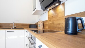 A modern kitchen with wooden countertops, a black Krups coffee maker, and a paper bag on the counter.