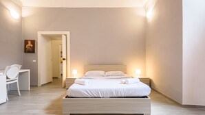 Une chambre bien rangée, avec un lit, des tables de chevet, un bureau et une chaise.