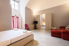 Une chambre à coucher avec un lit, un canapé rouge, un miroir et une télévision.
