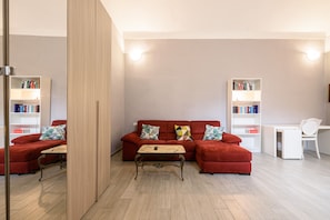 Un salon moderne avec un canapé rouge, une table basse en bois et deux étagères blanches.