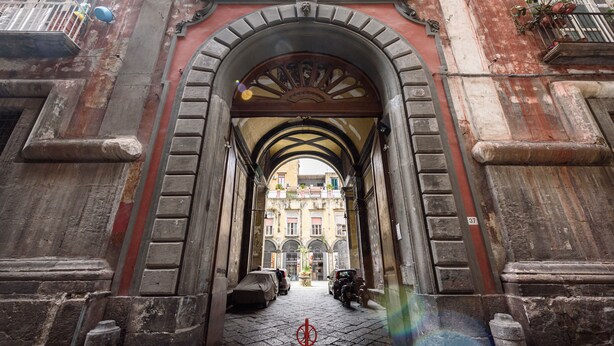 Une entrée en arc de cercle, avec un chemin pavé menant à un bâtiment.