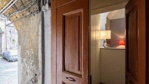 Une porte en bois qui donne sur une pièce où se trouvent une lampe et un lit.