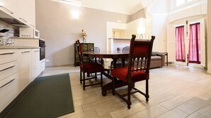 Une cuisine moderne avec des meubles blancs, une table à manger entourée de chaises rouges et une grande fenêtre agrémentée de rideaux.