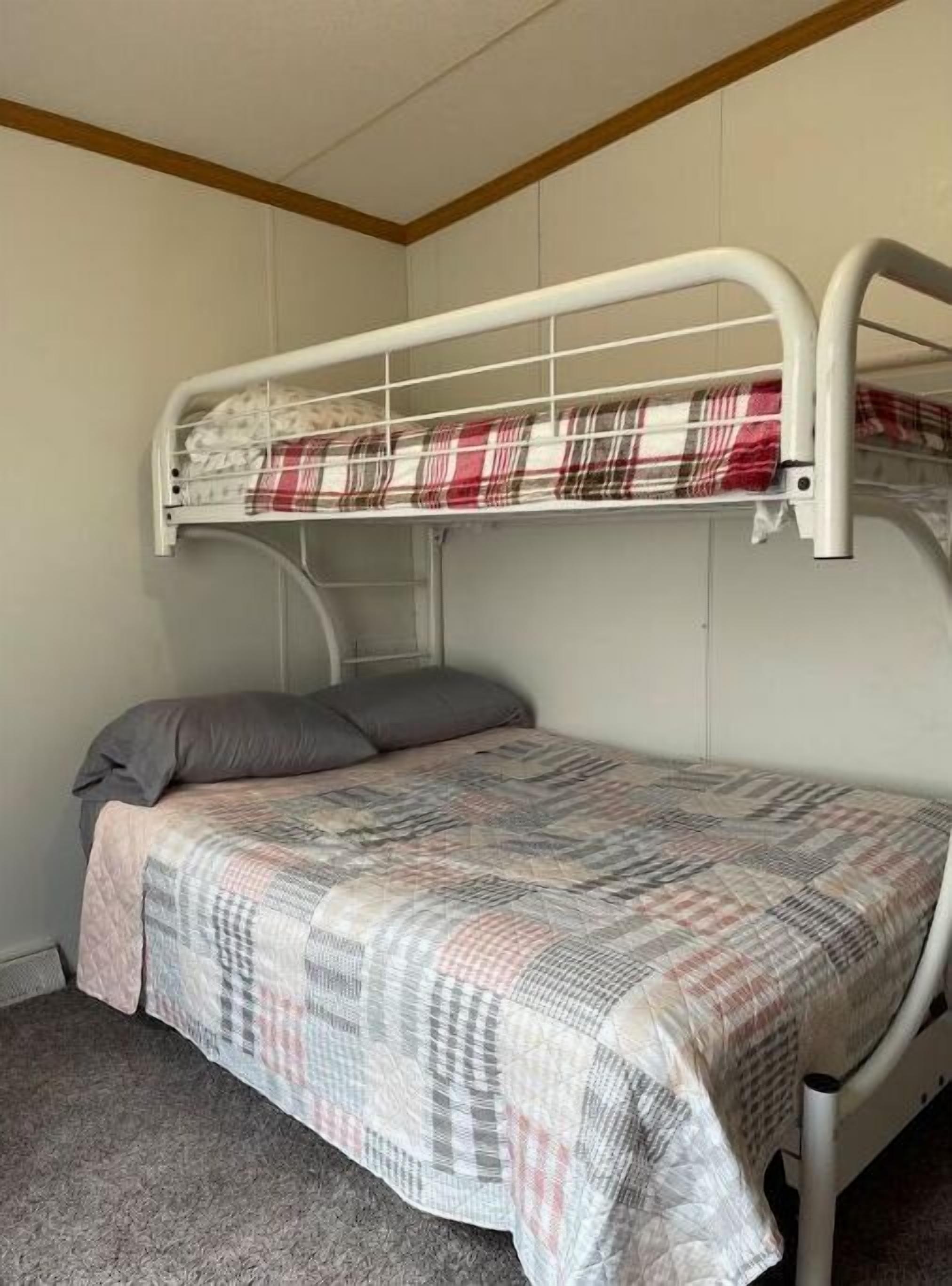 A bunk bed with a plaid bedspread and two pillows.