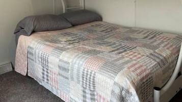 A bunk bed with a plaid bedspread and two pillows.