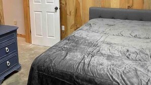 A bedroom with a bed, a dresser, and a door. - Woofpackshack #4 (West Leyden)