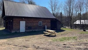 A rustic wooden building with a metal roof, a single door, and a small window. - Woofpackshack #4 (West Leyden)