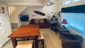 Um espaço compacto com mesa de jantar, sofá, televisão e janela com persianas.